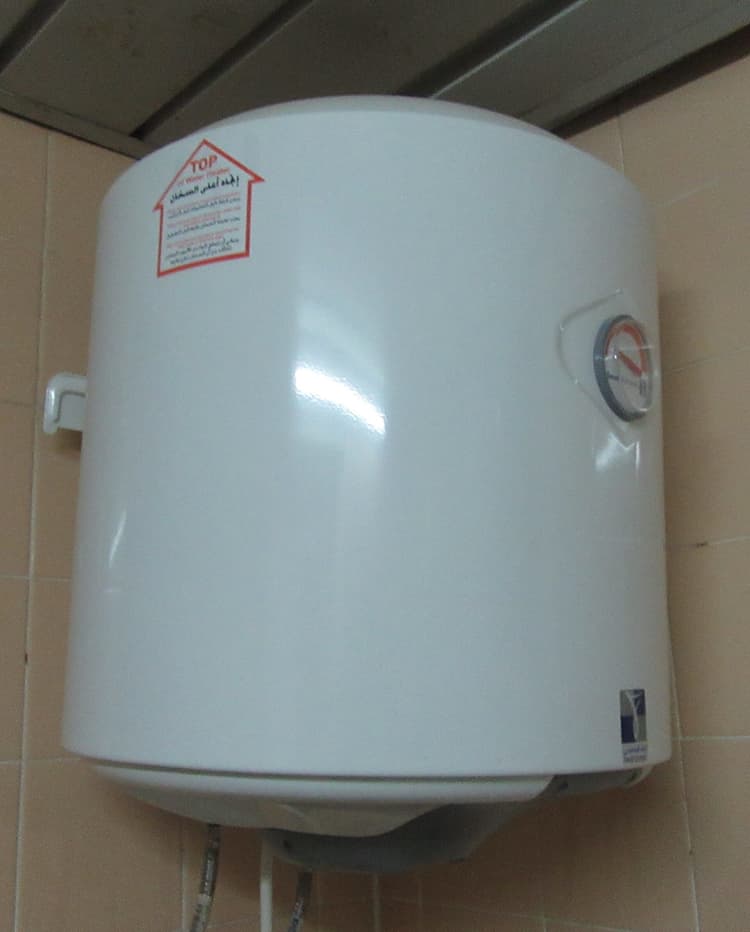 A white electric storage water heater against a garage wall